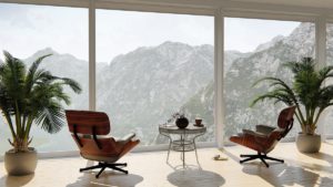 Elegantes Wohnzimmer mit zwei modernen roten Sesseln und einem kleinen Tisch zwischen ihnen, positioniert vor einem großflächigen Fenster mit atemberaubendem Blick auf felsige Berge.