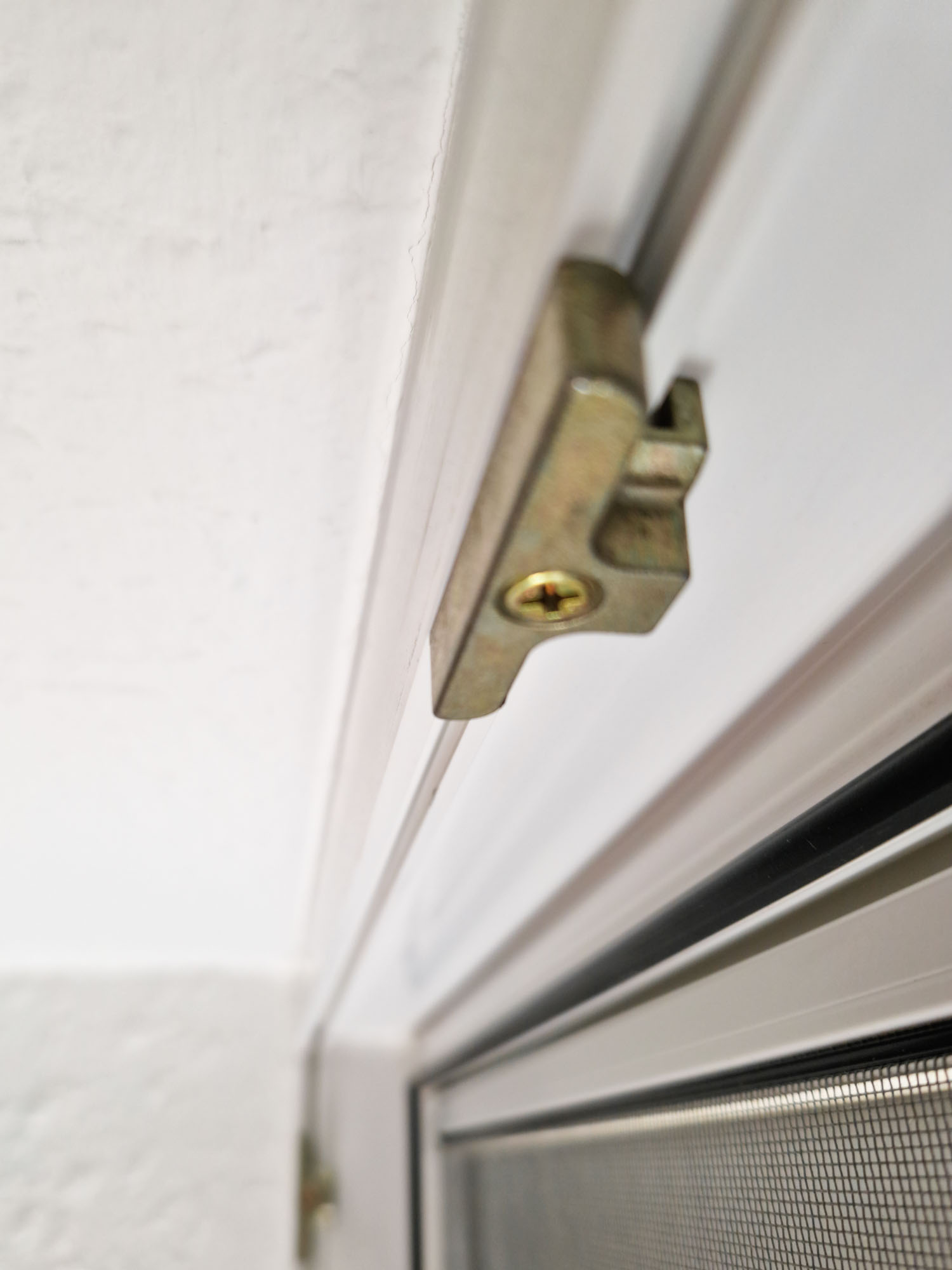 Nahaufnahme einer Fensterschließe mit integriertem Hitzeschutz, fokussiert auf die Sicherheitsfeatures und die Montage am Fensterrahmen.