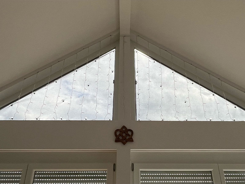 Innenansicht eines Dreiecksfensters mit Hitzeschutz, das effektiv das Sonnenlicht filtert und den Innenraum vor übermäßiger Wärme schützt, demonstriert in einer klaren und einfachen Darstellung.